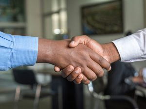 Dua orang profesional berjabat tangan sebagai simbol negosiasi bisnis yang sukses