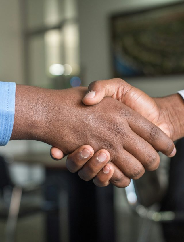 Dua orang profesional berjabat tangan sebagai simbol negosiasi bisnis yang sukses