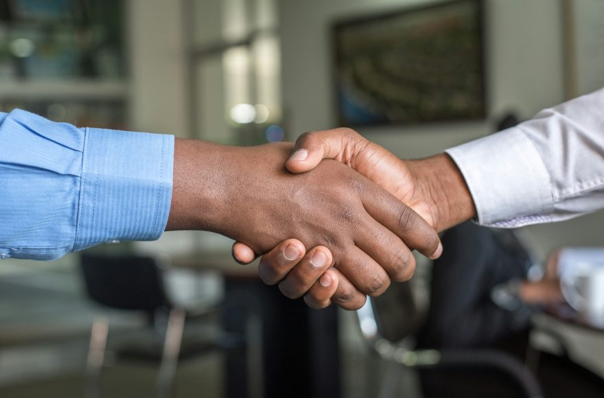 Dua orang profesional berjabat tangan sebagai simbol negosiasi bisnis yang sukses